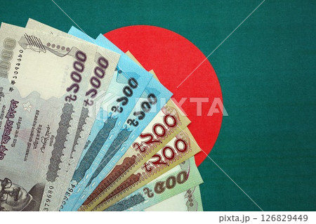 Bangladeshi taka money bills in big amount lies on Bangladesh flag close up 126829449