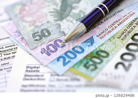 Argentine pesos money bills in big amount lies on table with pen and tax forms close up 126829486