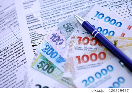 Argentine pesos money bills in big amount lies on table with pen and tax forms close up 126829487