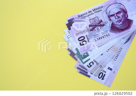 Mexican pesos money bills in big amount lies on yellow color table close up 126829502