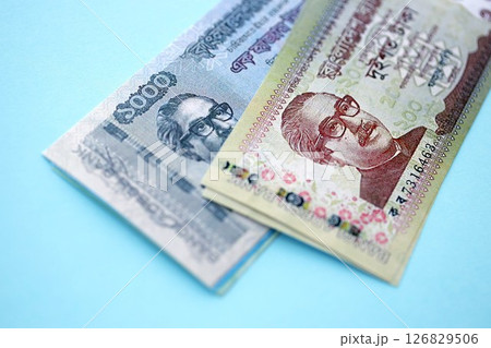 Bangladeshi taka money bills in big amount lies on teal color table close up Bangladeshi taka money bills in big amount lies on teal color table close up 126829506