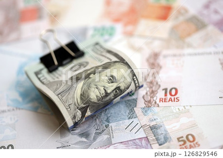 Bunch of US dollar bills lies on big amount of Brazilian reais banknotes close up 126829546