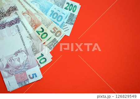 Close up of brazilian reais money bills in big amount on red. Pile of Brazil real currency banknotes 126829549