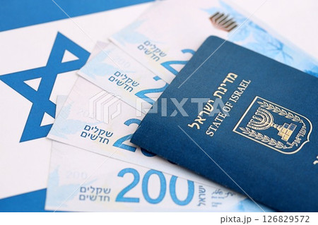 Israel New Shekels banknotes and passport on flag. The current Israel money bills and pass 126829572