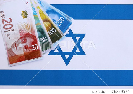 Israel New Shekels banknotes on national flag. The current Israel money bills lies on flag 126829574