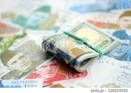 Bunch of US dollar bills lies on big amount of Pakistan rupees banknotes close up 126829588