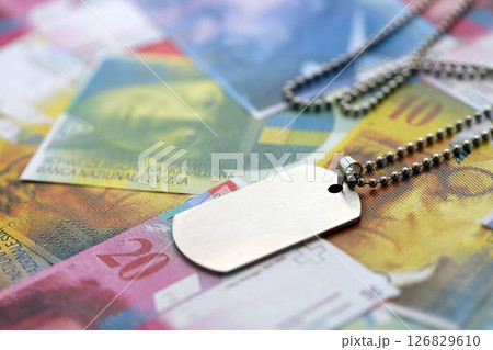 Swiss franc banknotes and military token. The current francs money bills and dogtags lies on table Swiss franc banknotes and military token. The current francs money bills and dogtags lies on table 126829610
