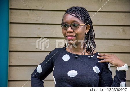 Confident African Woman Wearing Polka Dot Sweater and Glasses Outdoors Confident African Woman Wearing Polka Dot Sweater and Glasses Outdoors 126830407