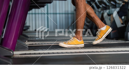 Workout and Fitness. Close-up of a person walking on a treadmill in bright yellow sneakers. Workout and Fitness. Close-up of a person walking on a treadmill in bright yellow sneakers. 126831322