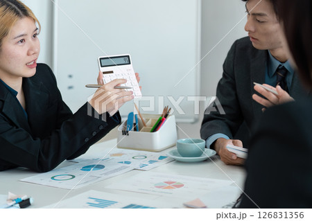 Diverse business professionals discussing financial strategy and calculations in a modern meeting. Diverse business professionals discussing financial strategy and calculations in a modern meeting. 126831356