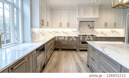 A large kitchen with white cabinets and a marble countertop 126832212