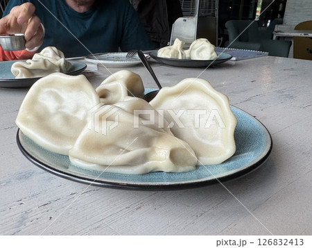traditional georgian dish khinkali lies on a plate with sauce in a restaurant. High quality photo 126832413