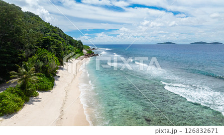 A beautiful white sandy beach with overhanging palm trees and crystal-clear waters stretching into the distance. Seychelles, La Digue. A beautiful white sandy beach with overhanging palm trees and crystal-clear waters stretching into the distance. Seychelles, La Digue. 126832671