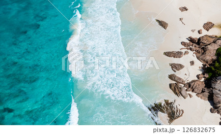 Turquoise ocean waves and white sands meeting rugged rock formations along the coast. La Digue, Seychelles. Turquoise ocean waves and white sands meeting rugged rock formations along the coast. La Digue, Seychelles. 126832675