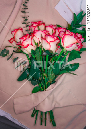 A bouquet of roses is wrapped in a coarse knit woolen sweater. A bouquet of roses is wrapped in a coarse knit woolen sweater. 126832803