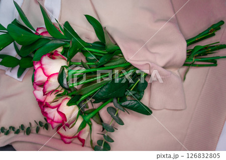 A bouquet of roses is wrapped in a coarse knit woolen sweater. A bouquet of roses is wrapped in a coarse knit woolen sweater. 126832805