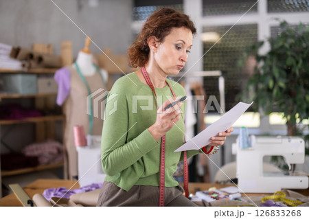 Sad female tailor businesswoman examines documents 126833268