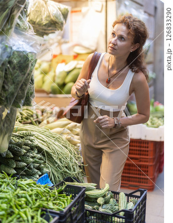 Woman inspecting fresh greens at street-side vegetable stall 126833290