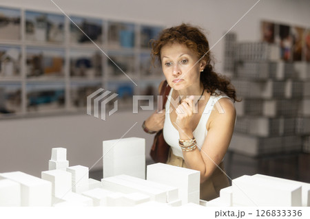 Curious woman observing architectural model in museum 126833336