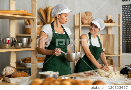 Two bakers knead dough in a bakery 126833437