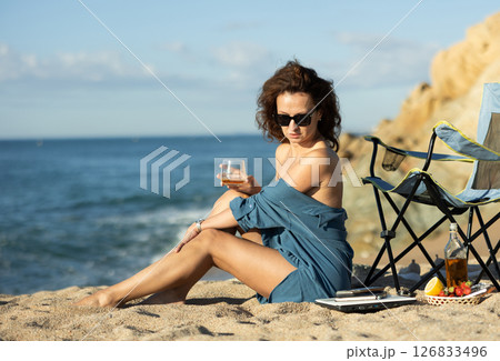 Seductive businesswoman drinking whiskey near shoreline Seductive businesswoman drinking whiskey near shoreline 126833496