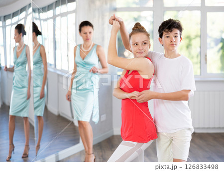 Teenage boy and girl performing waltz in pair during dance lesson Teenage boy and girl performing waltz in pair during dance lesson 126833498