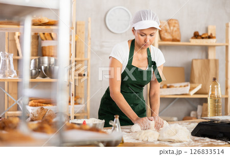 Woman kneading dough in the shape of a sausage 126833514