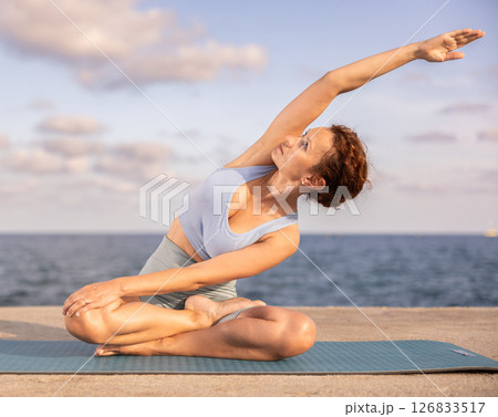 Yoga practice on embankment, female athlete fulfil carry out padmasana svastikasana, Siddhasana Yoga practice on embankment, female athlete fulfil carry out padmasana svastikasana, Siddhasana 126833517