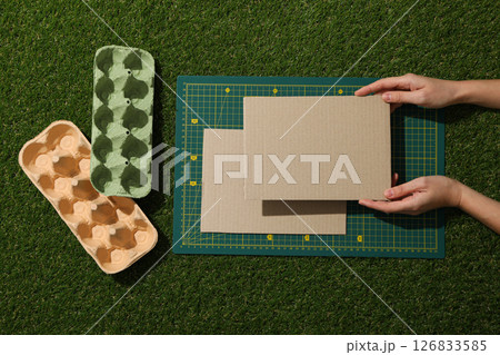 Drawing and paper materials for upcycling in hands on green background, top view 126833585