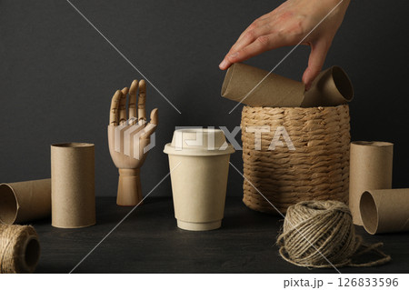 Paper materials for upcycling in hand, wooden hand, twine and basket on gray background 126833596
