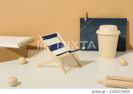 Paper cup, box, notepad and handmade figure on beige background, close up 126833600