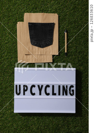 Light box with text, paper bag and denim pocket on green background, top view 126833610
