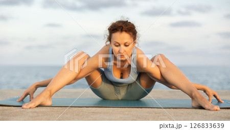 Yoga practice on embankment, female athlete fulfil carry out Upavishta Konasana 126833639