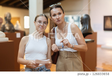 Young woman with teen daughter walk around museum, view sculpture in museum hall 126833658