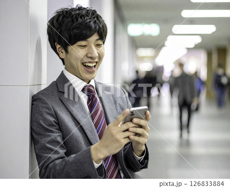 スマートフォンを見て大笑いする男子高校生 126833884