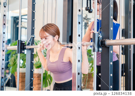 女性トレーナーからの指導を受けて筋トレをする女性 女性トレーナーからの指導を受けて筋トレをする女性 126834138