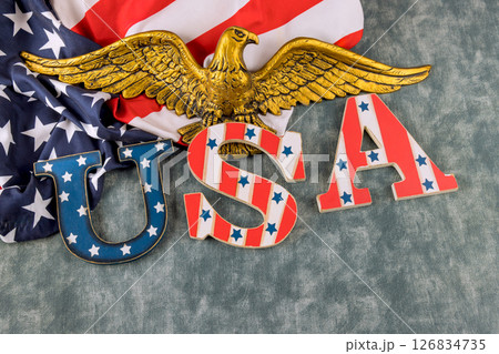 USA letters adorned with stars stripes alongside an eagle emblem on backdrop of American flag. 126834735