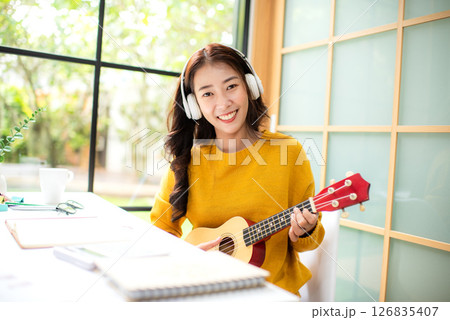 Young woman happy listen music for chill and playing guitar after finish work. 126835407
