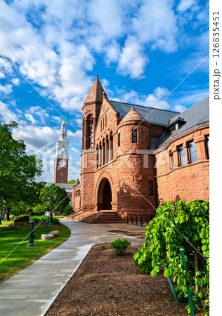 The historic Billings Library, built in red sandstone with Romanesque Revival architecture, stands beside the white clock tower of Ira Allen Chapel on the University of Vermont campus in Burlington The historic Billings Library, built in red sandstone with Romanesque Revival architecture, stands beside the white clock tower of Ira Allen Chapel on the University of Vermont campus in Burlington 126835451