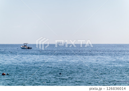 Calm blue sea with the silhouette of a large ship on the horizon 126836014