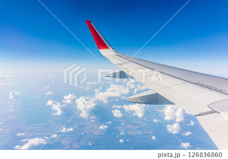 View from the airplane window at a beautiful cloudy sky and the airplane wing 126836860