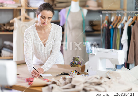 Woman tailor draw dress pattern of product on paper 126839421