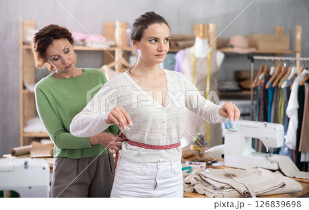 Woman tailor takes measurements from female client 126839698