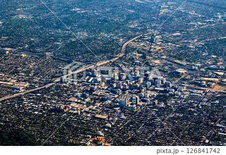 Expansive aerial view of San Jose, California, featuring a dense urban downtown core surrounded by sprawling residential neighborhoods, visible highways, and scattered green spaces under clear Expansive aerial view of San Jose, California, featuring a dense urban downtown core surrounded by sprawling residential neighborhoods, visible highways, and scattered green spaces under clear 126841742
