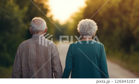 elderly couple walking hand in hand along serene path, enjoying nature beauty together 126843287