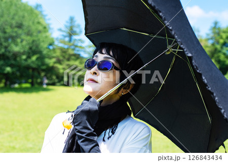 日傘とストールと手袋といサングラスで紫外線対策をした中年女性 日傘とストールと手袋といサングラスで紫外線対策をした中年女性 126843434