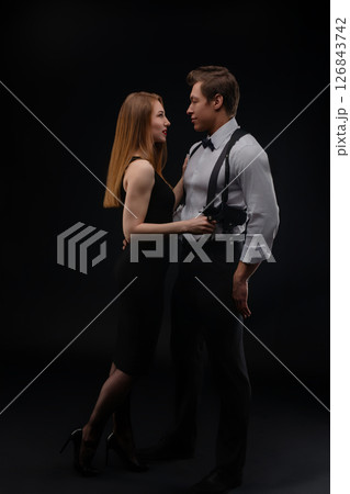 Couple in elegant attire sharing a romantic moment against a dark background 126843742