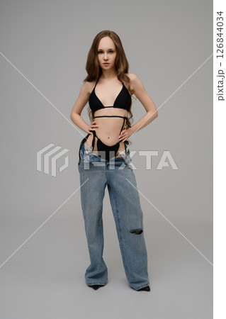 Model confidently poses in trendy swimwear and oversized jeans 126844034