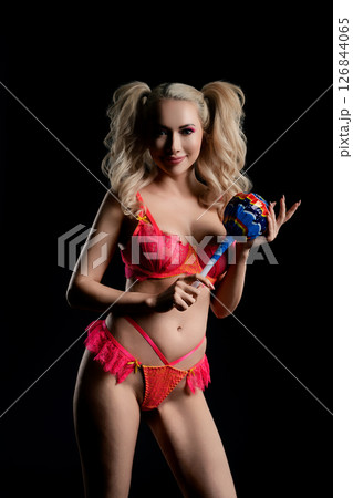 Woman in vibrant lingerie holding a colorful candy in a playful studio setting 126844065