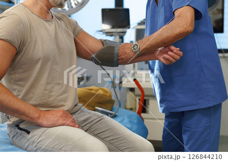 Doctor taking patient's blood pressure using digital blood pressure monitor. 126844210